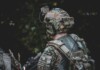 When the Threat Comes from Above: The New Reality of Body Armor A close-up image of an individual wearing camouflage clothing and a tactical vest equipped with multiple pouches and accessories.