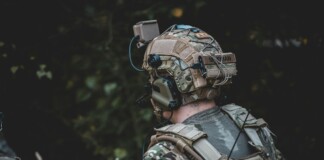 When the Threat Comes from Above: The New Reality of Body Armor A close-up image of an individual wearing camouflage clothing and a tactical vest equipped with multiple pouches and accessories.