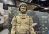 Balancing Protection and Performance: The Evolution of Military Textiles and Personal Protective Equipment (PPE) at Sioen Industries A modern military protective system displayed at a defense exhibition, featuring advanced camouflage textiles, modular body armor, and integrated soldier protection technologies developed for contemporary operational environments.