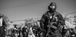 Where Protection Meets Performance: An Exclusive Interview with ANORAK CEO Dimitris Koskovos A heavily equipped tactical officer stands watch amid a public event, highlighting the importance of readiness and protective equipment in complex operational environments.