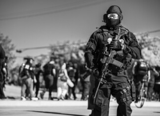 Where Protection Meets Performance: An Exclusive Interview with ANORAK CEO Dimitris Koskovos A heavily equipped tactical officer stands watch amid a public event, highlighting the importance of readiness and protective equipment in complex operational environments.